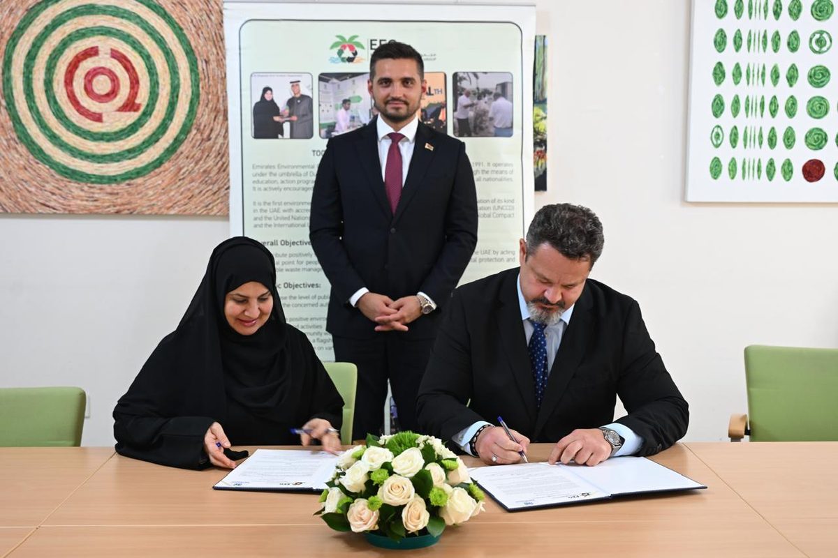 Dr. Habiba Al Mar'ashi and Maksim Barziankou sign the MoU, with H.E. Aliaksei Zhaldybin standing behind